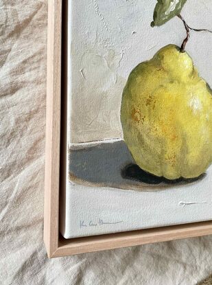 A small original still life painting of a quince with leaves on a neutral background