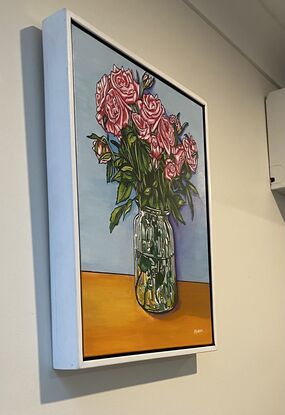 Pink roses in a glass vase, painted in a bright popart/cartoon  style with bright, cheerful light blue ax orange background. Realistic but with a slight cartoon twist in the bright colours and bold outlines. 
Set in a white timber frame that makes the bright colours pop. 