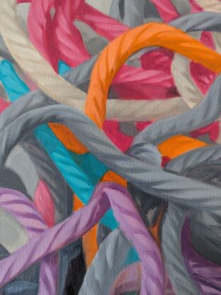 A birds eye view of a colourful pile of woollen threads on a grey background.