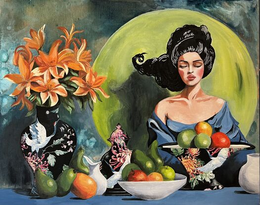 Woman sitting at a table with a vase of lilies, some bowls of fruit - oranges, apples, avocados 