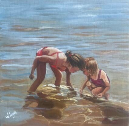 Two young girls crouch heads together in the shallows  of  the tidal break looking at something below the water’s surface.