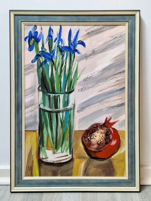 A bouquet of blue irises in transparent vase and large open pomegranate