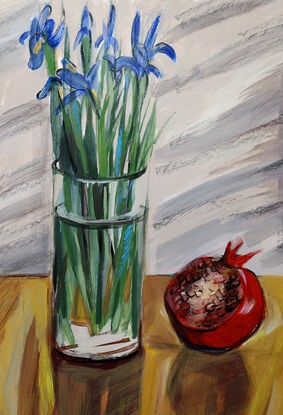 A bouquet of blue irises in transparent vase and large open pomegranate