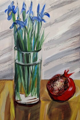 A bouquet of blue irises in transparent vase and large open pomegranate