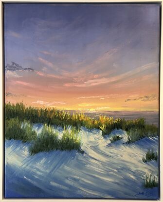 Sunrise over the ocean with colourful sky, delicate clouds and blue shadows across the sands.  This painting is frames.  Painted in blues and orange/yellos.