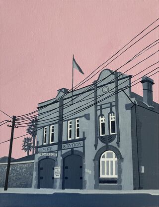 Old fire station building in grey tones with a pink sky