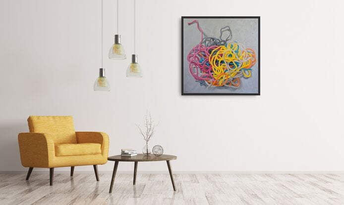 A birds eye view of a colourful pile of woollen threads on a grey background.