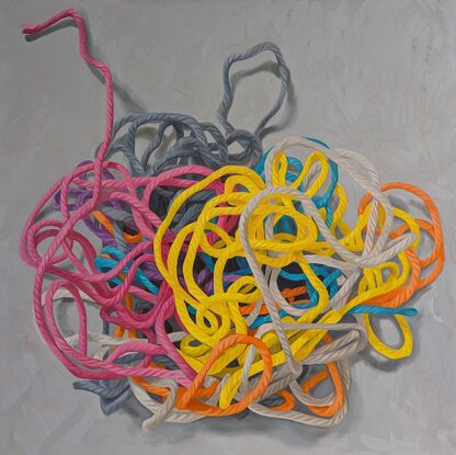 A birds eye view of a colourful pile of woollen threads on a grey background.