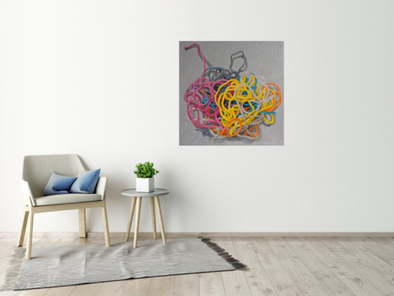 A birds eye view of a colourful pile of woollen threads on a grey background.