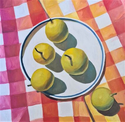 Looking down onto a plate of light green nashi pears sitting on a brightly checked oink, orange and yellow tablecloth.