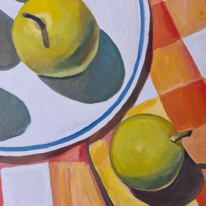 Looking down onto a plate of light green nashi pears sitting on a brightly checked oink, orange and yellow tablecloth.