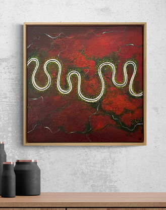 A vibrant and textured aerial landscape titled 'The Red Land of Wonder'. The painting features a vivid red expanse with a river meandering horizontally across the canvas. Dark green trees are dotted along the river.