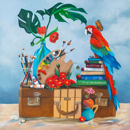 Parrot on a suitcase with art materials and flowers, on a beach. 