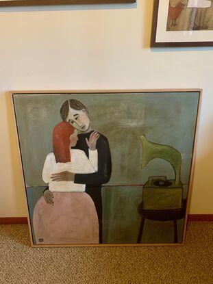 The painting depicts a man and woman embracing -- they are dancing. There is a gramophone on a stool beside them. 