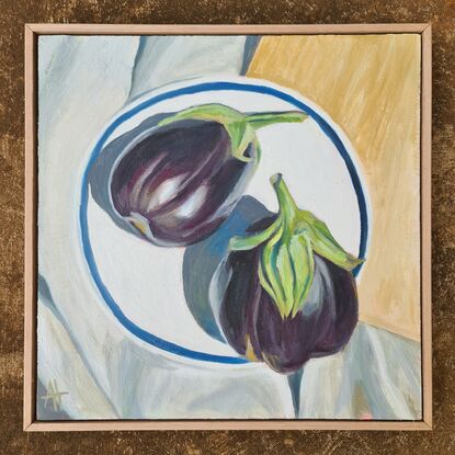 Looking down onto two purple eggplants on a white plate with blue rim.