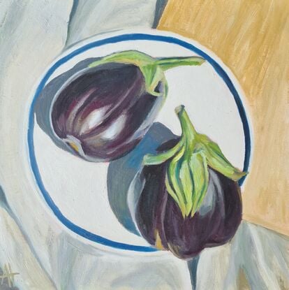 Looking down onto two purple eggplants on a white plate with blue rim.