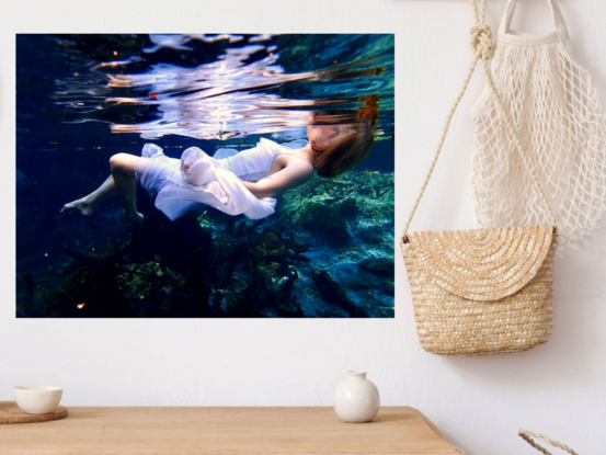 Young woman floating on the surface of the water  in a white dress - capturing beautiful reflections of light.