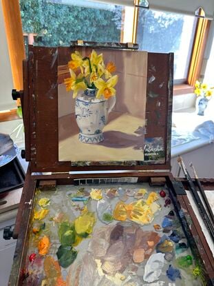 blue and white ceramic jug with yellow daffodils on a kitchen bench with sunlight streaming in.