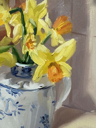 blue and white ceramic jug with yellow daffodils on a kitchen bench with sunlight streaming in.