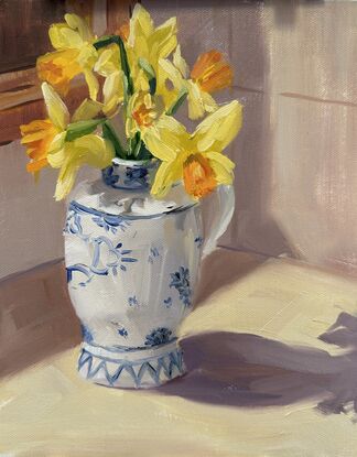 blue and white ceramic jug with yellow daffodils on a kitchen bench with sunlight streaming in.