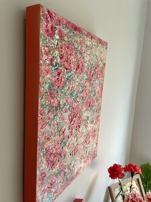 The textured pink and red coloured flowers stand out predominantly over  a green and turquoise  background.