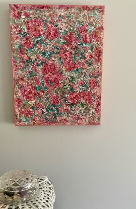 The textured pink and red coloured flowers stand out predominantly over  a green and turquoise  background.