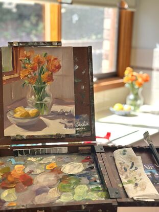 Ranunculus in a glass vase with lemons in a sunny kitchen corner.