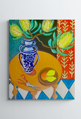 Lemon Banksia in a black vase on a pink table with lemons, scissors and a blue harlequin tile floor