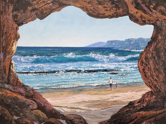 A view from a cave overlooking a pristine beach with a adult and child walking/playing to add some life.