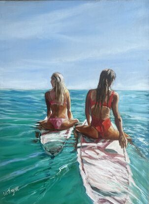 Two tanned women sit astride surfboards watching the ocean’s horizon 