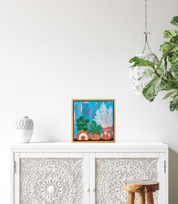 Three terracotta pots with plants sitting on a shelf. 