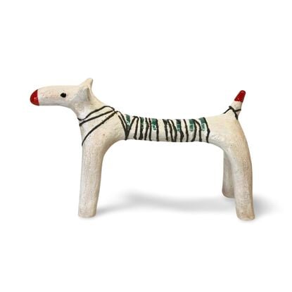 This ceramic sculpture features a dog-like figure with elongated legs and a stylised body. The body was wrapped in copper wire and fused into the white glaze. A few jade-coloured stripes highlight the oxidised copper.