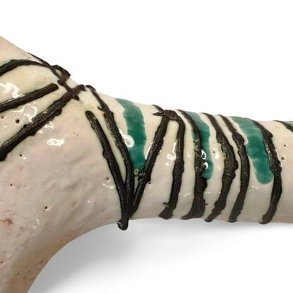 This ceramic sculpture features a dog-like figure with elongated legs and a stylised body. The body was wrapped in copper wire and fused into the white glaze. A few jade-coloured stripes highlight the oxidised copper.