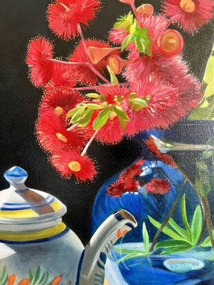 Red gum blossom and bottlebrush in a vase, with green apples and tea. 