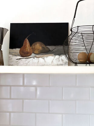 Two beurre bosc pears on a white tablecloth with a vintage scalloped knife in front of them