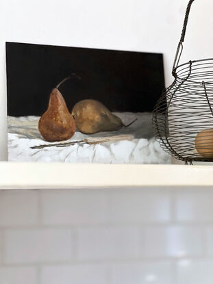 Two beurre bosc pears on a white tablecloth with a vintage scalloped knife in front of them