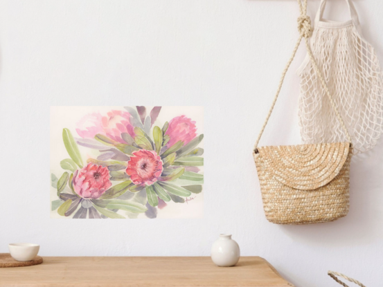 An arrangement of five pink protea flowers and foliage.