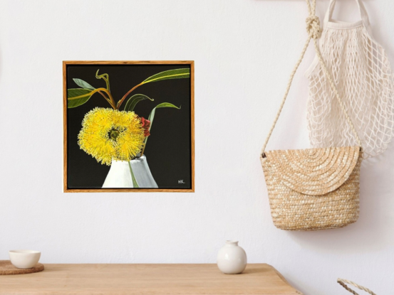 The painting features a bright yellow Eucalyptus Pressiana flower in full bloom, set against a dark background. Its vibrant stamens and green-grey leaves with bug marks are meticulously detailed. The flower rests in a simple white vase, creating a striking contrast with the moody backdrop.