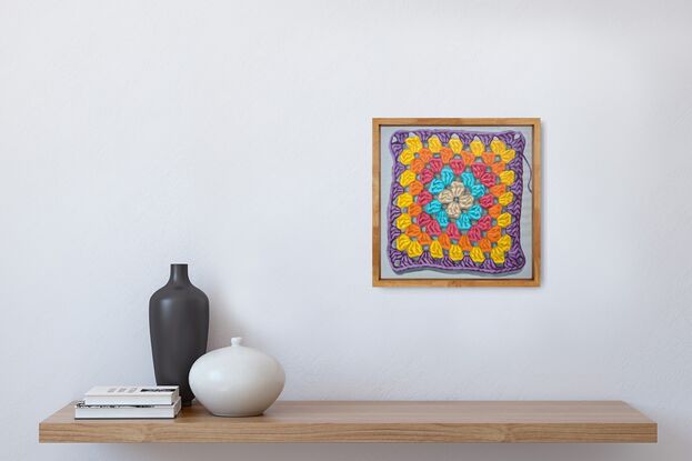 A crochet granny square with 6 rounds of pastel colours on a light grey background.