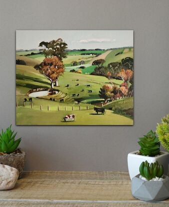 Rural Australia with green rolling hills and paddock. Cows are scattered throughout the scene.