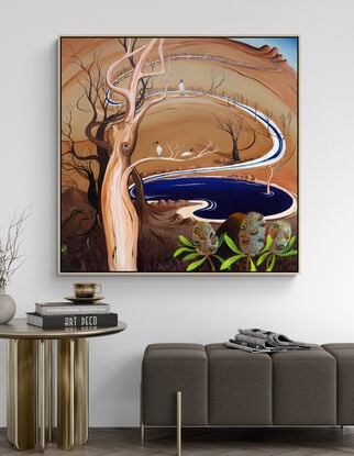 The Watering Hole by Tania Chanter is an abstract landscape painting, the canvas is bathed in warm caramel tones, creating an atmosphere of earthy richness and tranquility. A blue watering hole takes centre stage and trees and ibis birds randomly dot the landscape.