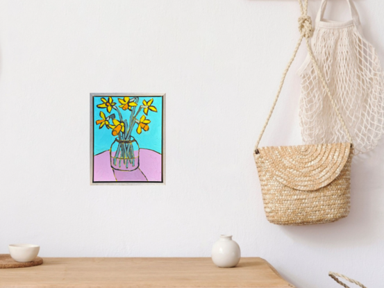 Daffodils in a large glass jar, sitting on a pink table