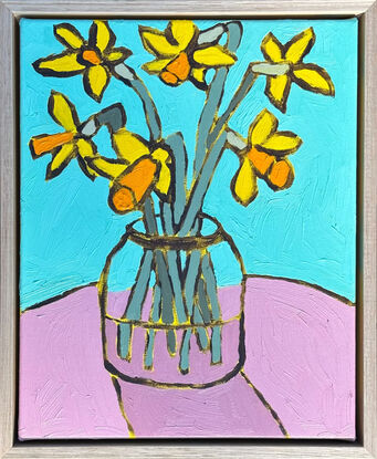 Daffodils in a large glass jar, sitting on a pink table