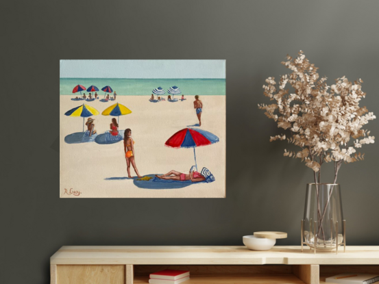 People laying on the beach under beach umbrellas in the sixties with ocean in distance.