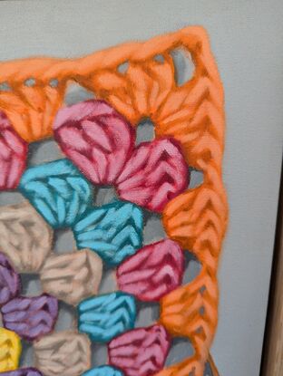 A crochet granny square with 6 rounds of bright colours on a light grey background.