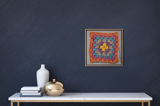 A crochet granny square with 6 rounds of bright colours on a light grey background.