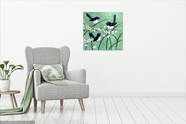 A family of three Willy Wagtails sitting together on pink and white flowers on a pale green background. The image is stretched around to cover the sides of the canvas. The birds are black and white and they are sitting on pink and white flowering branches. 