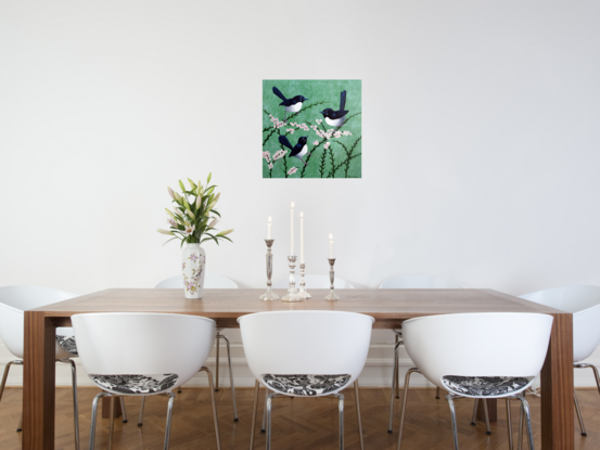 A family of three Willy Wagtails sitting together on pink and white flowers on a pale green background. The image is stretched around to cover the sides of the canvas. The birds are black and white and they are sitting on pink and white flowering branches. 