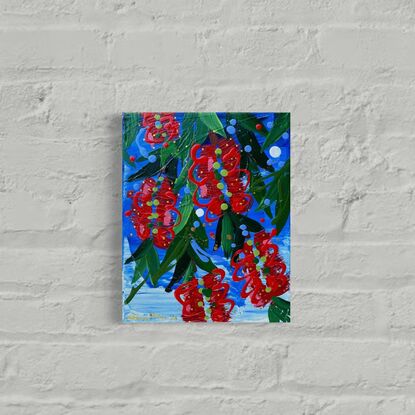 Close up of 5 bright red bottlebrush flowers hanging from a tree with a bright blue sky background. 