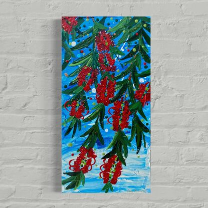 Close up of 10 bright red bottlebrush flowers hanging from a tree with a bright blue sky background. 